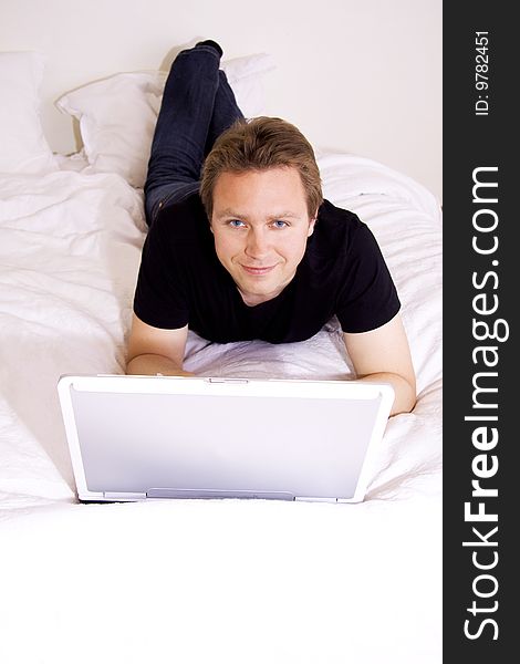 Man using a laptop in the bedroom. Man using a laptop in the bedroom