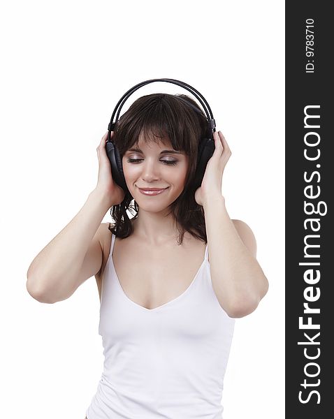 The beautiful girl in a white vest listens to music and smiles, having closed eyes from pleasure. The beautiful girl in a white vest listens to music and smiles, having closed eyes from pleasure