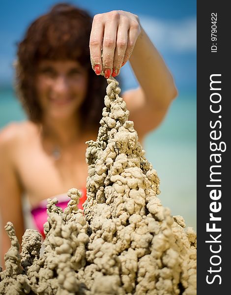 A woman building a sandcastle on the beach.