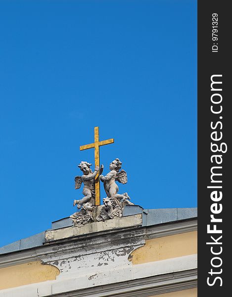Sculptures of angels are holding a gold cross on the roman catholic church of St. Ekaterina in St.Petersburg