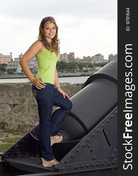 Beautiful lady smiling and standing in a cannon, with Havana view background. Beautiful lady smiling and standing in a cannon, with Havana view background