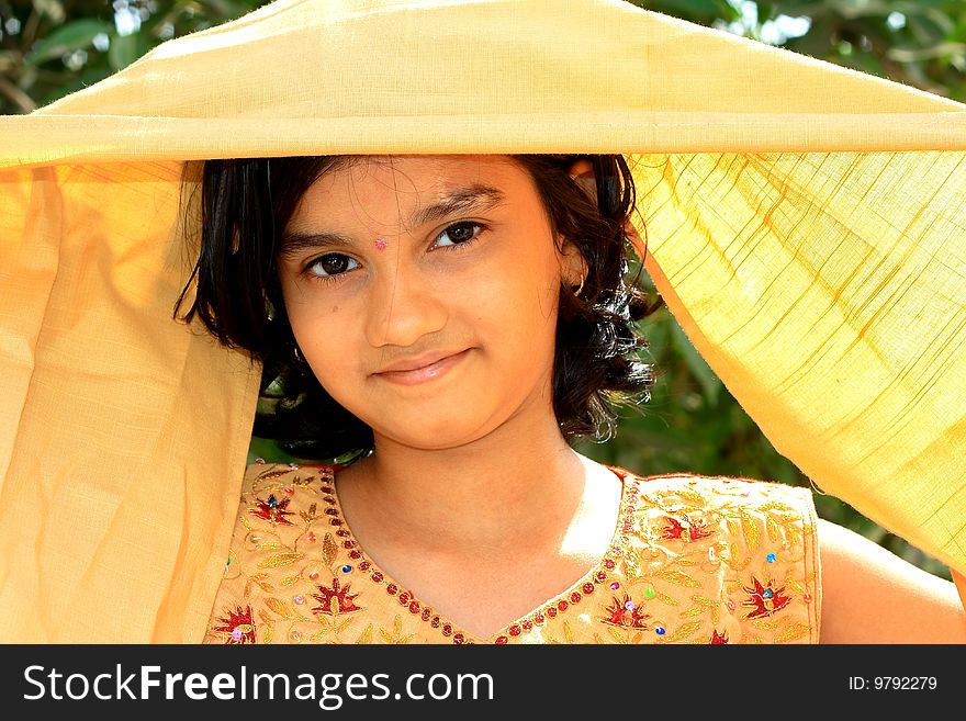 A traditional Indian girl lifting her golden veil to reveal her bright and beautiful face. A traditional Indian girl lifting her golden veil to reveal her bright and beautiful face.