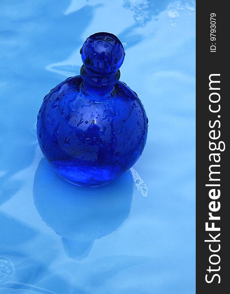 Blue small bottle on a wet glazing background. Blue small bottle on a wet glazing background