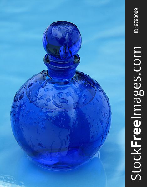 Blue small bottle on a wet glazing background. Blue small bottle on a wet glazing background