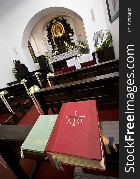 Interior of a small Roman catholic chapel with a nun praying at the side of the altar.