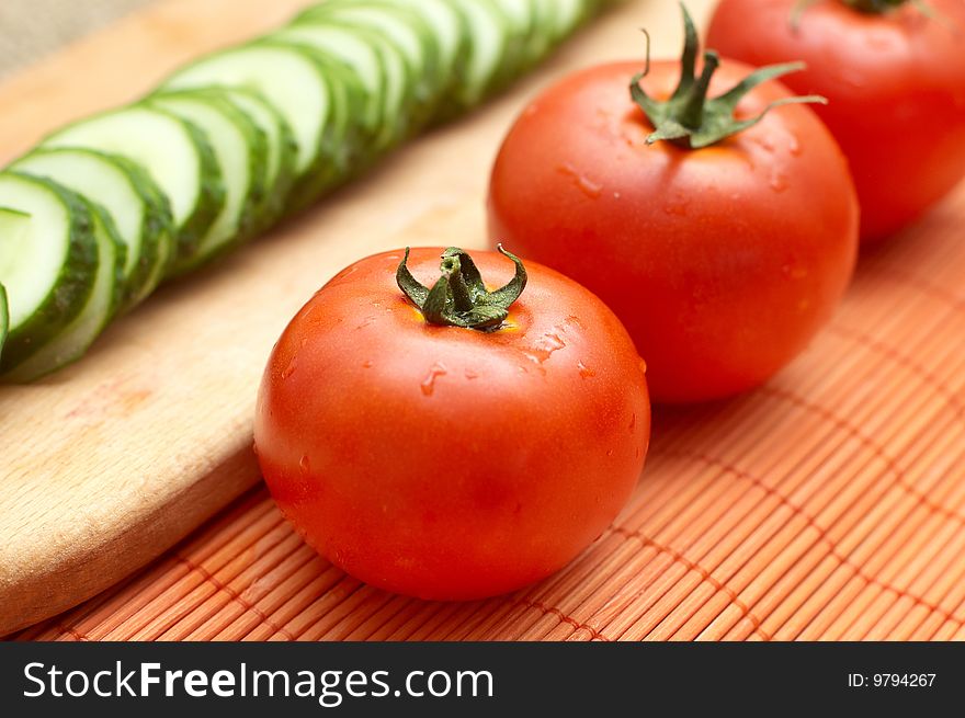 Fresh ripe tomatoes with droplets on bamboo mat