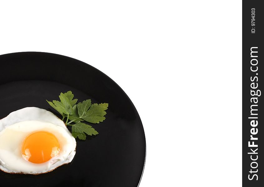 Fried egg on a black plate isolated on white