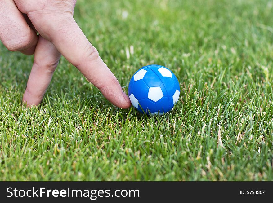 Man hand plaiyng role of soccer player with small blue ball. Man hand plaiyng role of soccer player with small blue ball