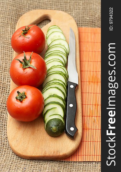 Kitchen still life: tomatoes, cucumber and knife on kitchen board. Kitchen still life: tomatoes, cucumber and knife on kitchen board