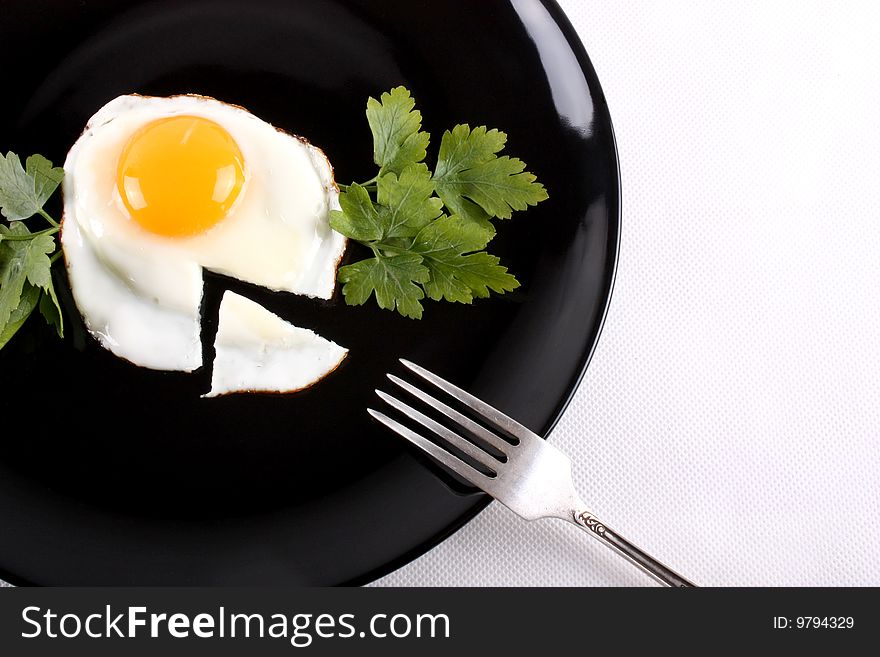 Fried egg on a black plate with a fork