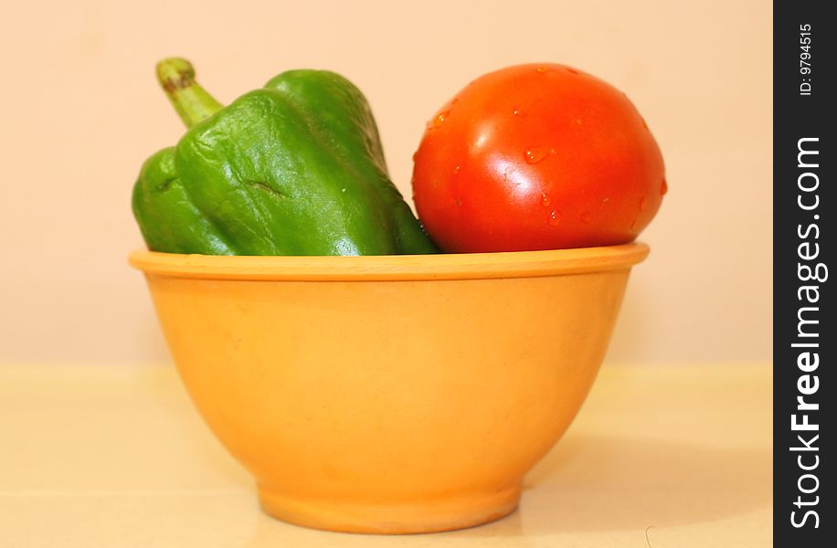 Two types vegetables-green capsicum and red tomato in a orange bowl. Two types vegetables-green capsicum and red tomato in a orange bowl.