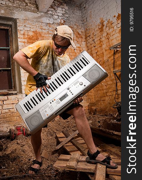 Musician plays a synthesizer in abandoned industrial interior