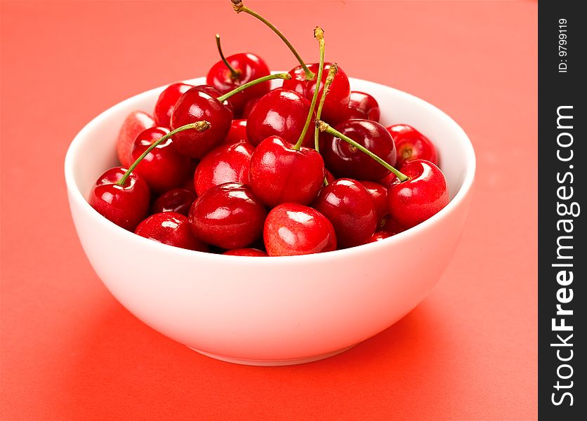 Cherries in white bowl on red presented. Cherries in white bowl on red presented