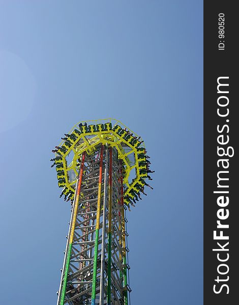 Free Fall Tower on a carnival area in bright sunlight. Free Fall Tower on a carnival area in bright sunlight