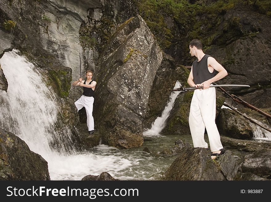 Waterfall area is a nice place to practice fencing outdoor. Two man with katanas. Waterfall area is a nice place to practice fencing outdoor. Two man with katanas