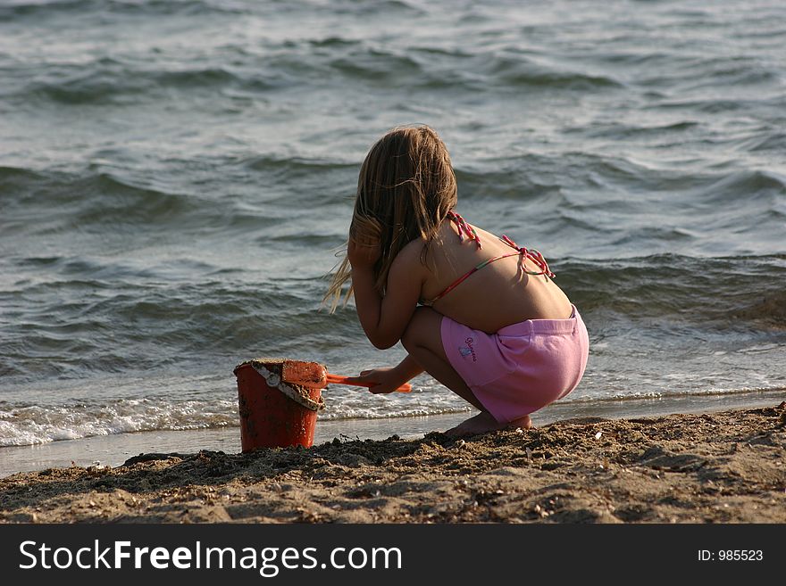 Little girl is playing with sand at beach. Little girl is playing with sand at beach