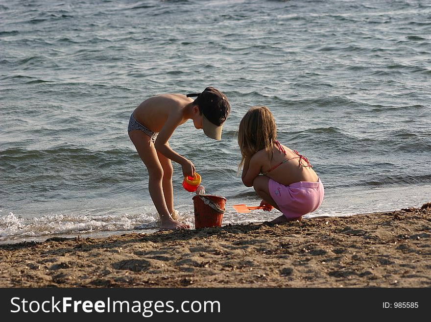 Little girl and little boy are playing with sand at beach. Little girl and little boy are playing with sand at beach