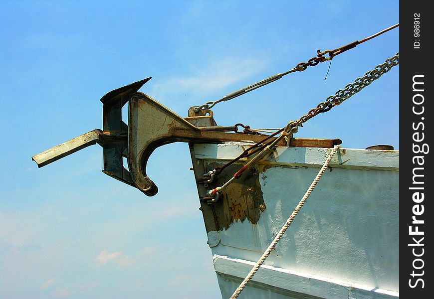 The anchor is riding on the front of a fishing boat as it comes into harbor. The anchor is riding on the front of a fishing boat as it comes into harbor.