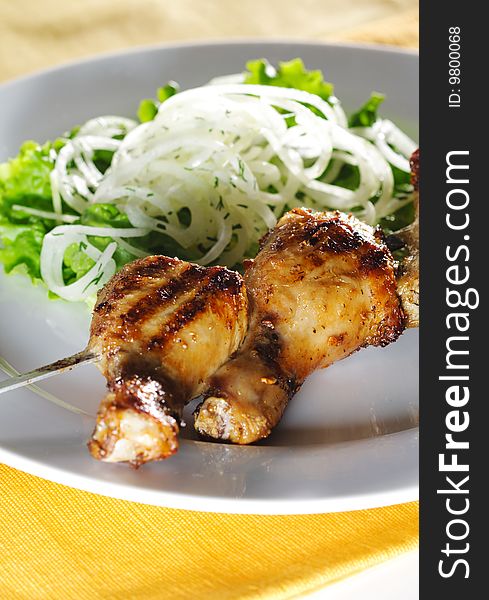 Grilled Chicken Legs on Skewer with Pickled Onions and Salad Leaf