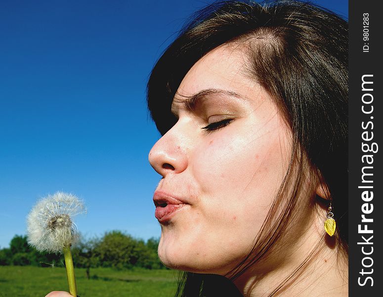 Young woman blowing on flower