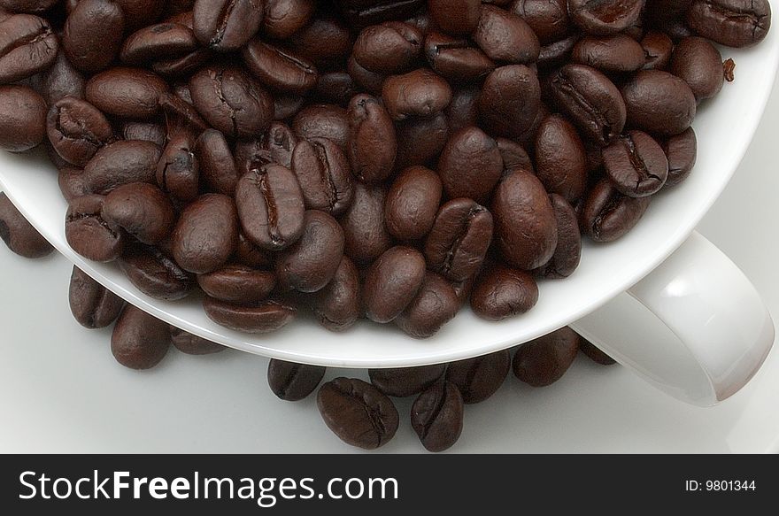 Cup and saucer filled with coffee beans.