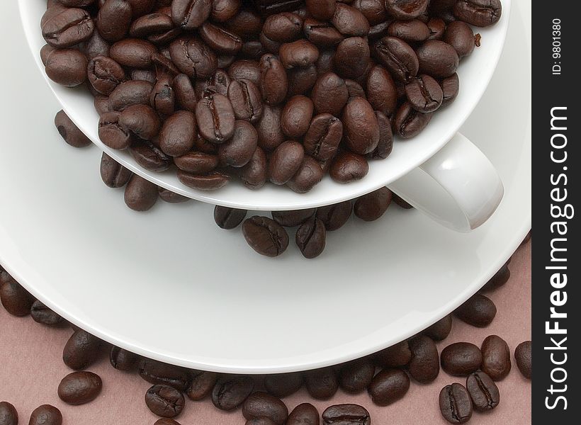 Cup and saucer filled with coffee beans.