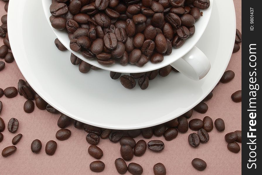 Cup and saucer filled with coffee beans.