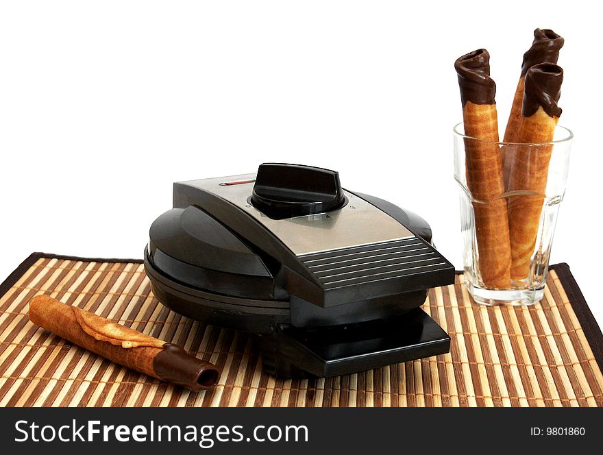 Wafer- roll with chocolate in a glass and waffle iron on a background. Wafer- roll with chocolate in a glass and waffle iron on a background