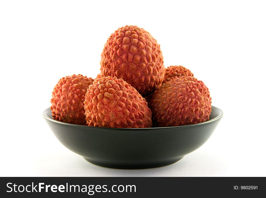 Group of lychee in a black dish with clipping and a white background
