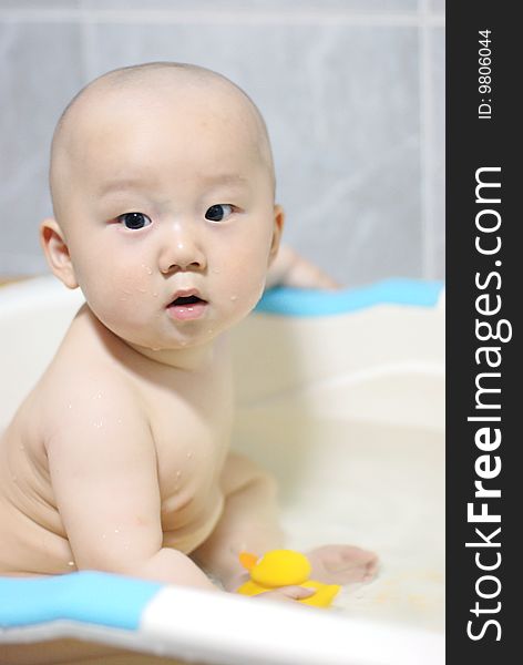 Asian baby boy holding  a yellow plastic duck in bath. Asian baby boy holding  a yellow plastic duck in bath