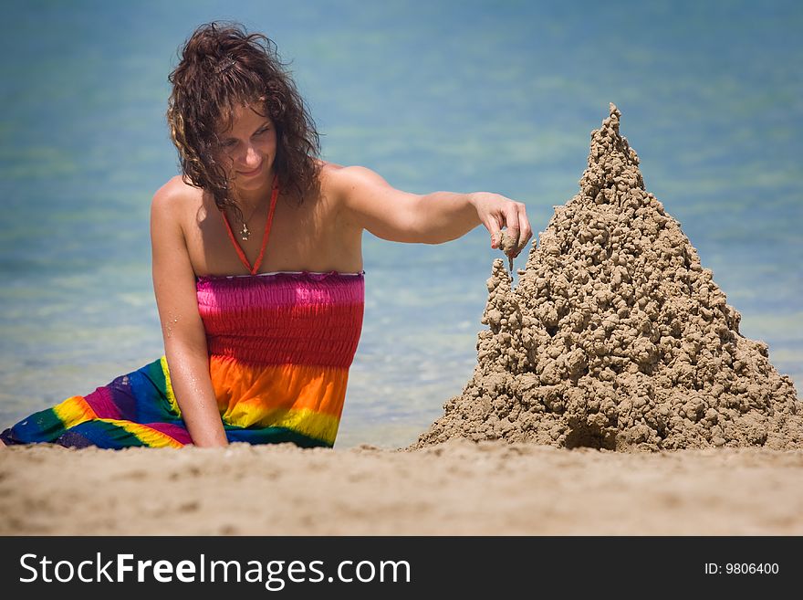 A woman building a sandcastle on the beach.