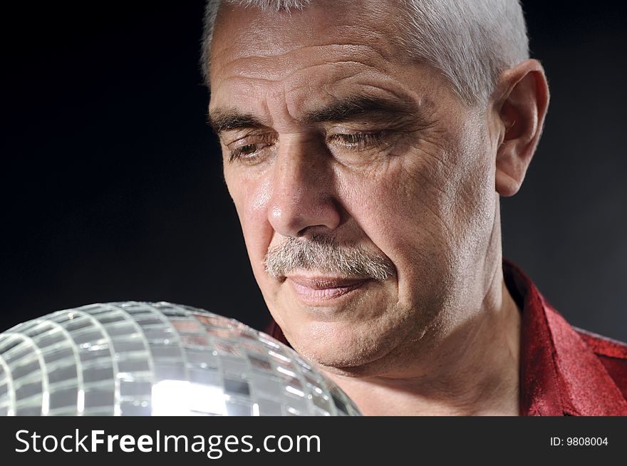 Old man looking at discoball isolated on black