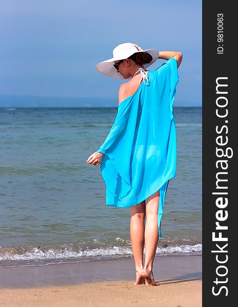 Brunette girl with white hat standing on the beach