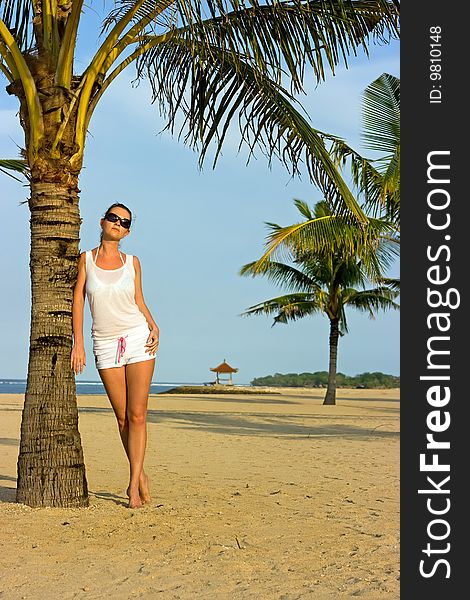 Brunette girl standing on the palm beach. Brunette girl standing on the palm beach