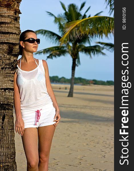 Brunette girl leaning at the beach palm. Brunette girl leaning at the beach palm