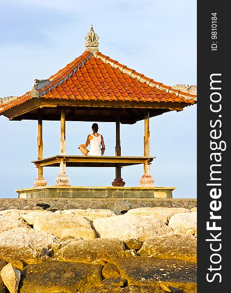 Brunette girl sitting in lotos pose and meditating in pagoda. Brunette girl sitting in lotos pose and meditating in pagoda