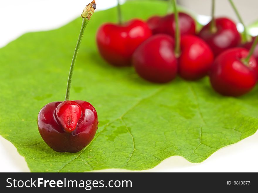 Fresh sweet cherry lies on green leaf