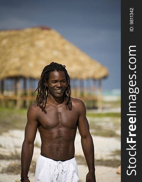 Black man walking on the beach over wood umbrella. Black man walking on the beach over wood umbrella