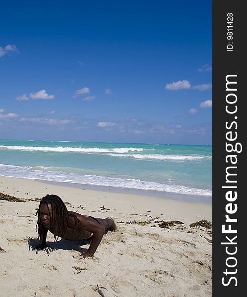 Black man making pumps ont the beach over blue sea and blue sky. Black man making pumps ont the beach over blue sea and blue sky