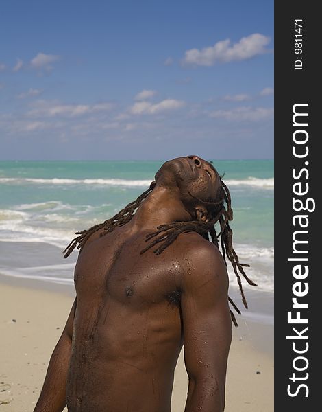 Black man tilting his head behind on the beach over blue sea and blue sky. Black man tilting his head behind on the beach over blue sea and blue sky