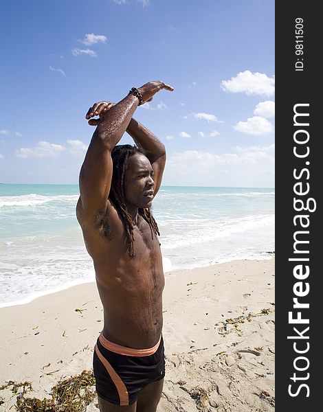 Black man raising arms ont the beach over blue sea and blue sky. Black man raising arms ont the beach over blue sea and blue sky