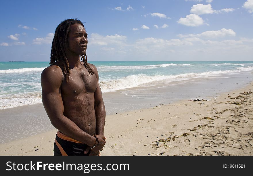 Black man thinking on the beach back in the blue sea over blue sky. Black man thinking on the beach back in the blue sea over blue sky