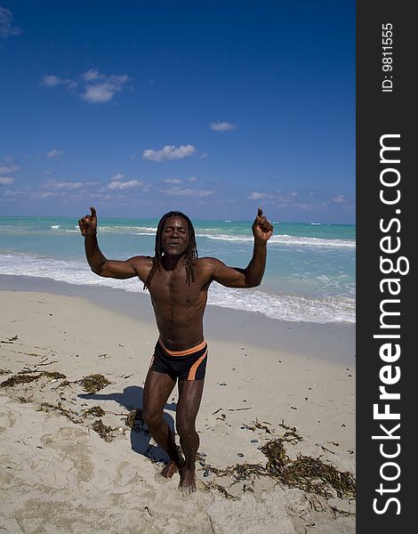 Black man dancing on the beach back in the blue sea over blue sky. Black man dancing on the beach back in the blue sea over blue sky