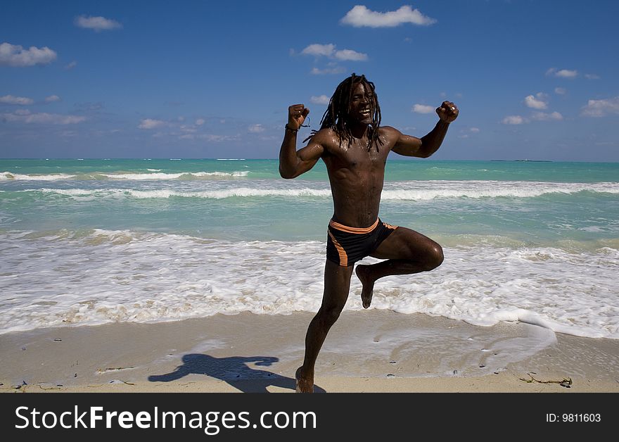 Black man jumping on the beach over blue sea and blue sky. Black man jumping on the beach over blue sea and blue sky