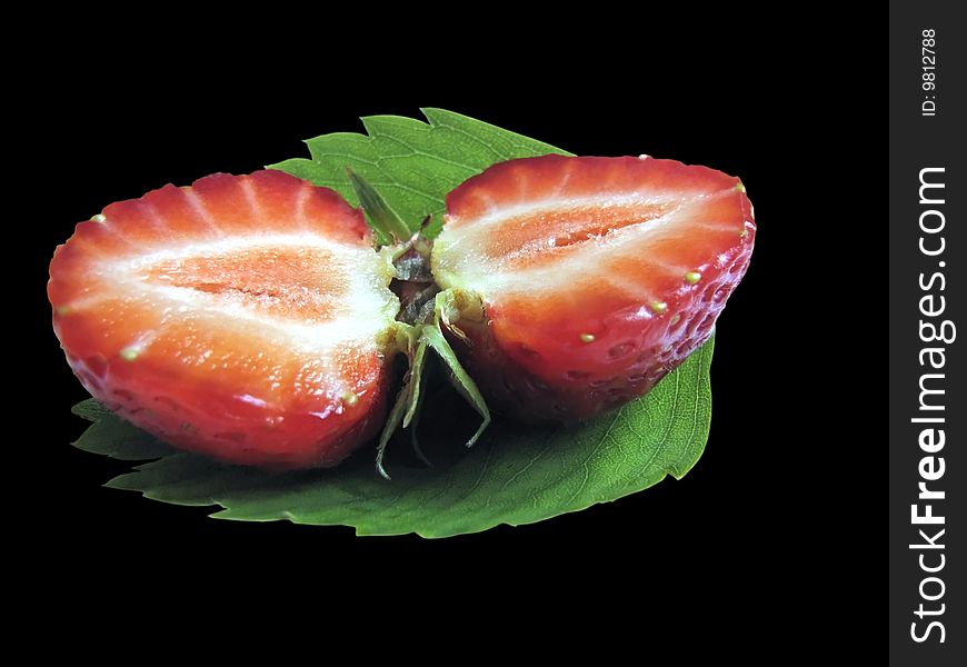 Close up halves of strawberry laying on a green leaf