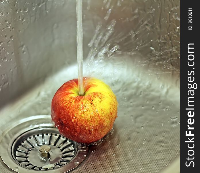 Water stream breaking about a red juicy apple. Water stream breaking about a red juicy apple