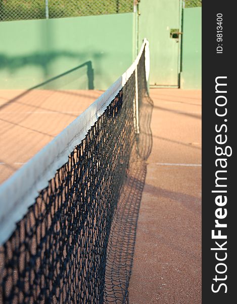 A clay court and the net of tennis. A clay court and the net of tennis