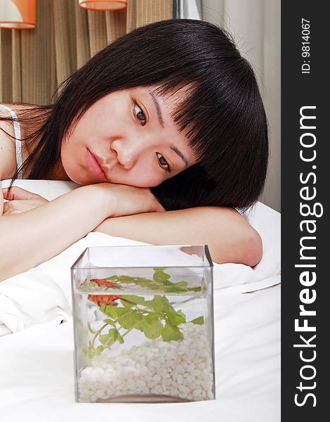 A beautiful Asian girl is seeing the expression of the goldfish on the bed. A beautiful Asian girl is seeing the expression of the goldfish on the bed.