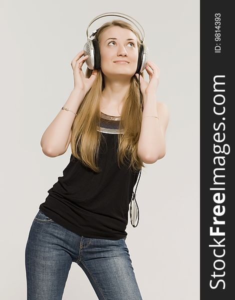 Young girl a blonde listens music through earpiecess