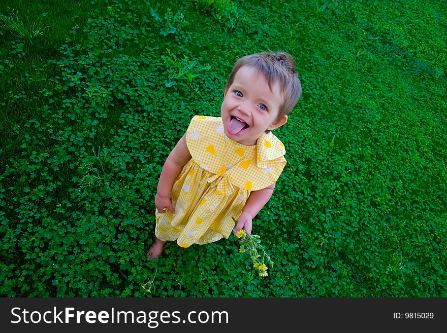 Portrait of little girl putting out her tongue on grass background. Portrait of little girl putting out her tongue on grass background